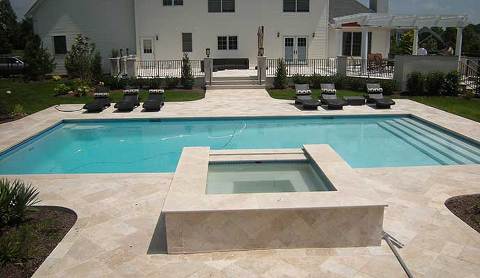A pool and spa with a light colored stone paving creates a sophisticated look.